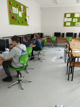 uczniowie na kole informatycznym uczą się programowania roboty