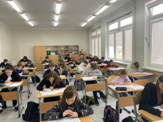 uczniowie siedzący na sali - rozwiązują zadania