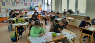 uczniowie siedzący na sali - rozwiązują zadania