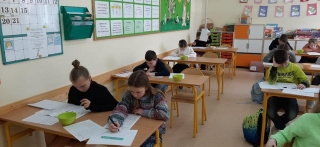 uczniowie siedzący na sali - rozwiązują zadania