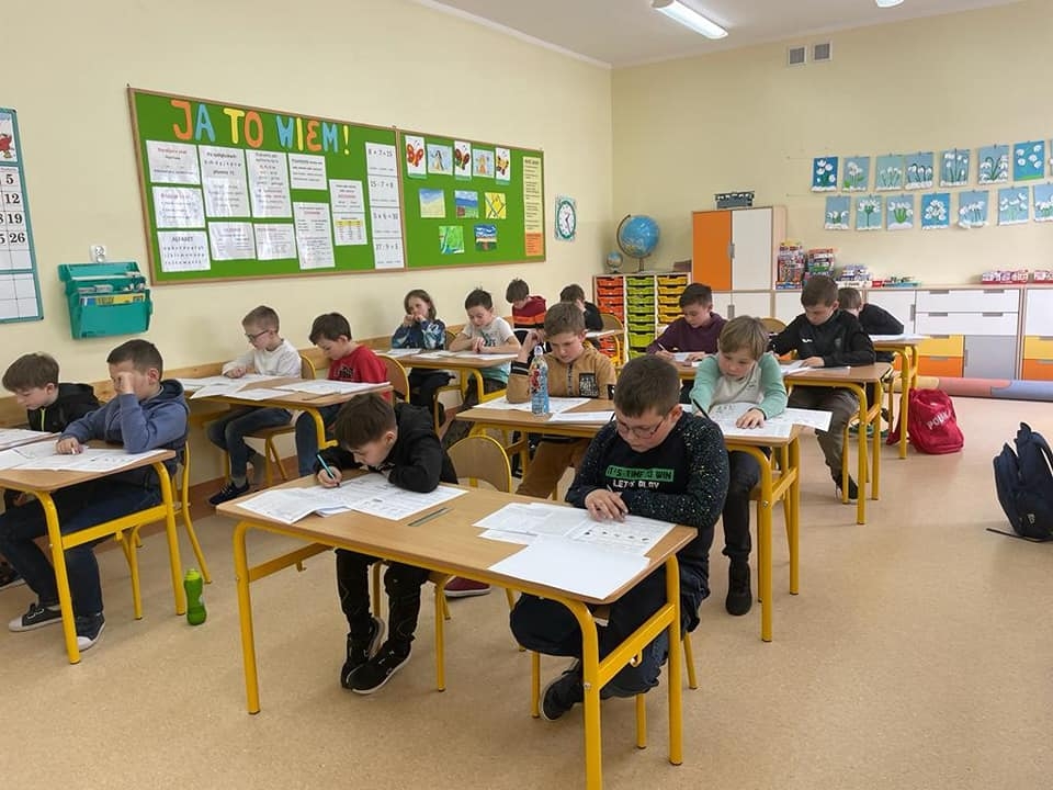 uczniowie siedzący na sali - rozwiązują zadania